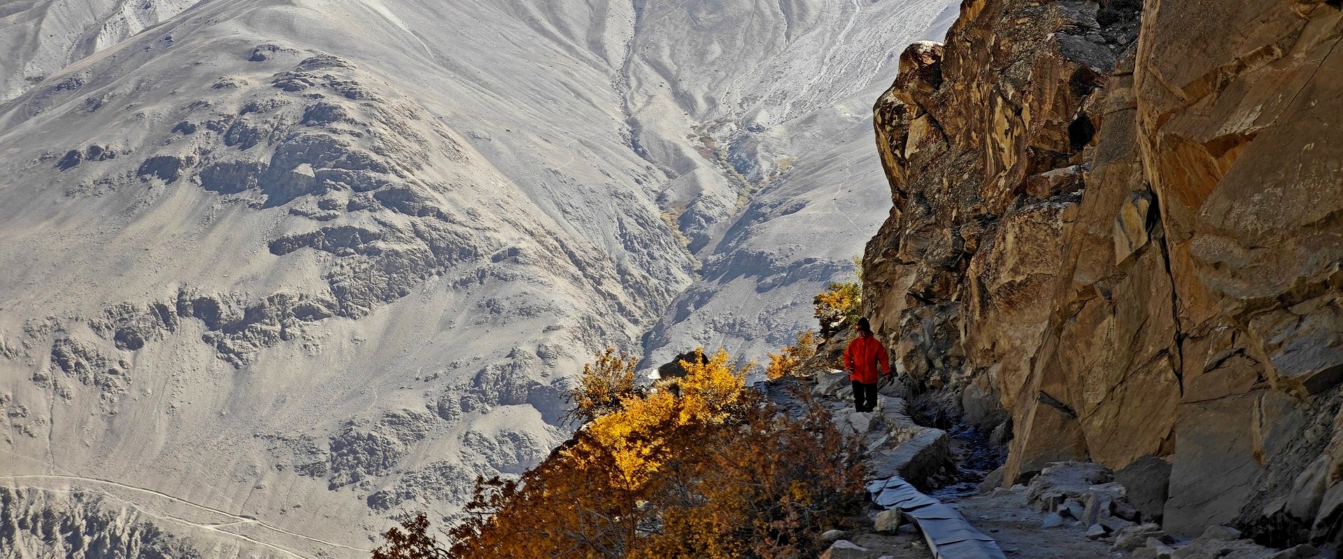 A walker on a cliffside trail high in the Pamirs